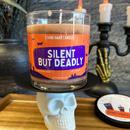 An orange silent but deadly stank away halloween candle on a spooky halloween background