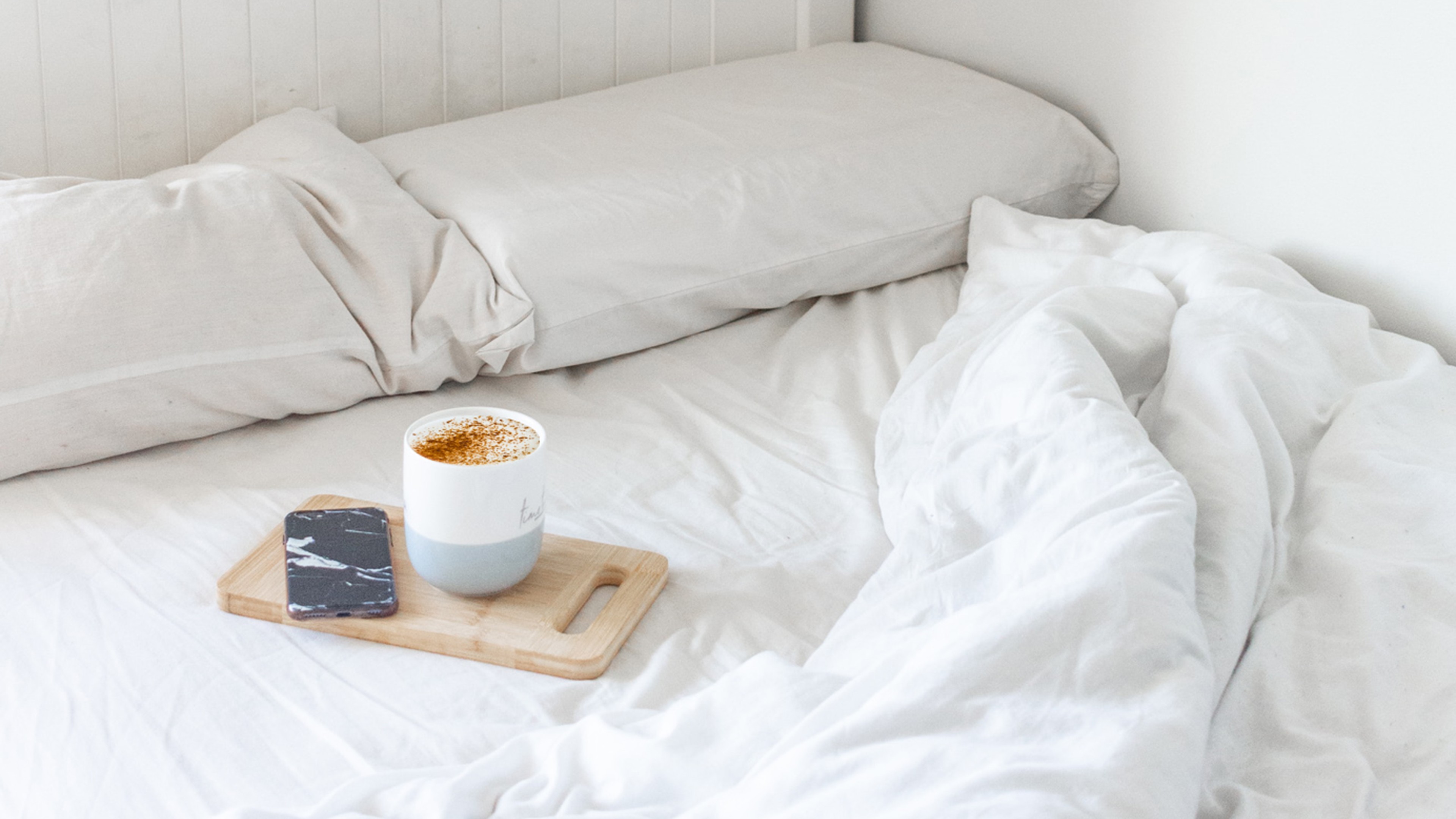 coffee and phone laying on the bed