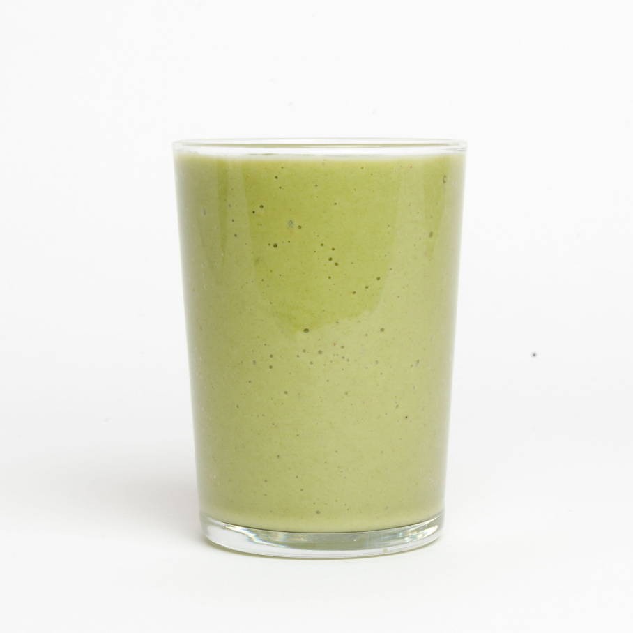 A glass with a light green smoothie shake filled to the brim