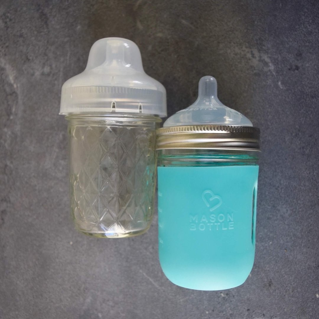 two glass baby bottles on concrete floor background