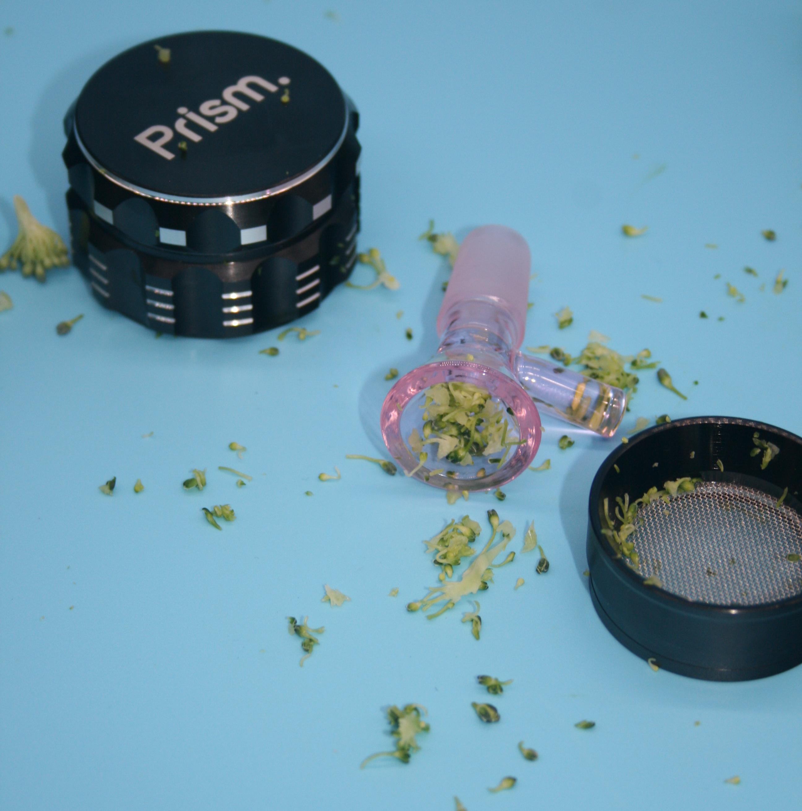Top-down view of a Prism Herb Grinder with freshly shredded material and a pink 14mm glass bowl slide packed for a session, illustrating how a precision grind optimizes flower for Prism modular bongs and all standard glass water pipes.