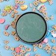 A tin of dirty dangles st patricks day hockey stick wax on a blue background with marshmallow cereal