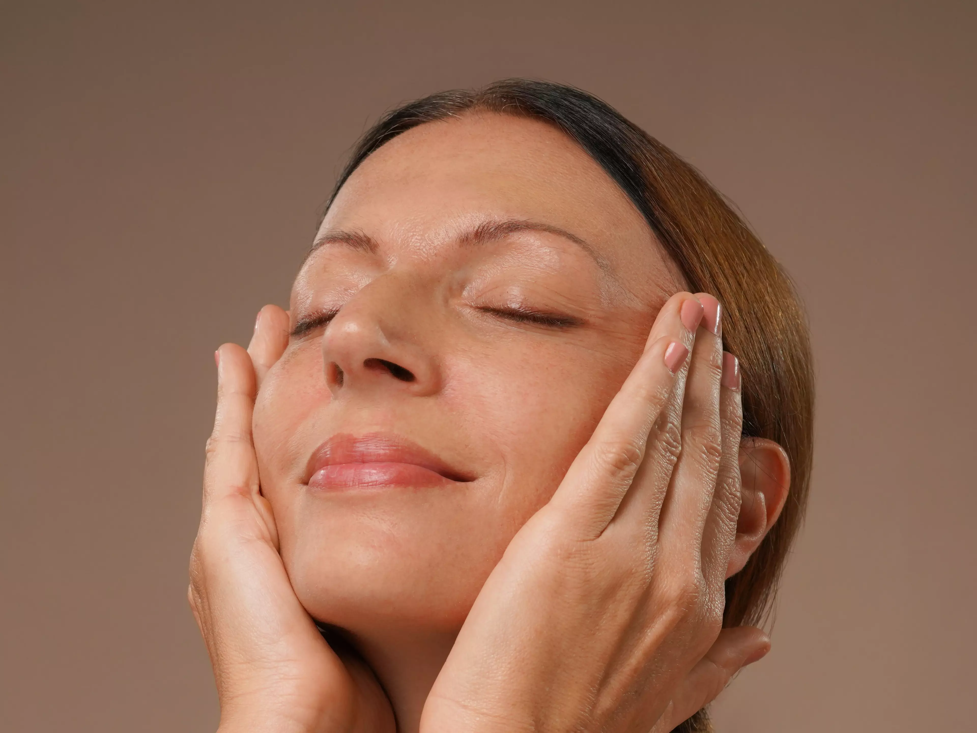 A woman massaging her face with serum
