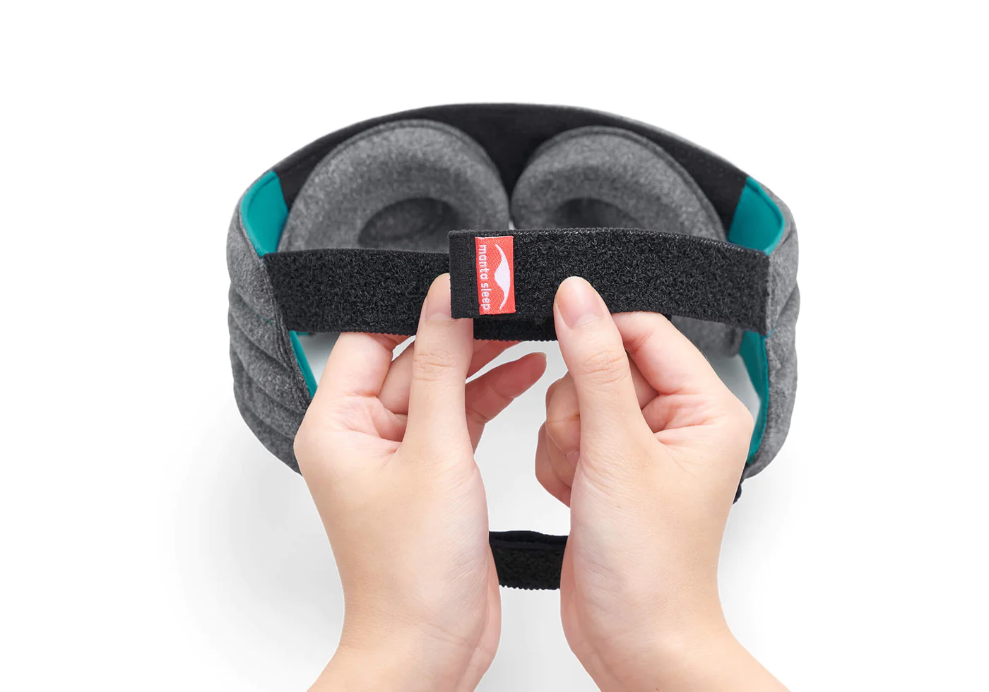 Hands holding the upper headband of a weighted sleep mask for gentle pressure relaxation.