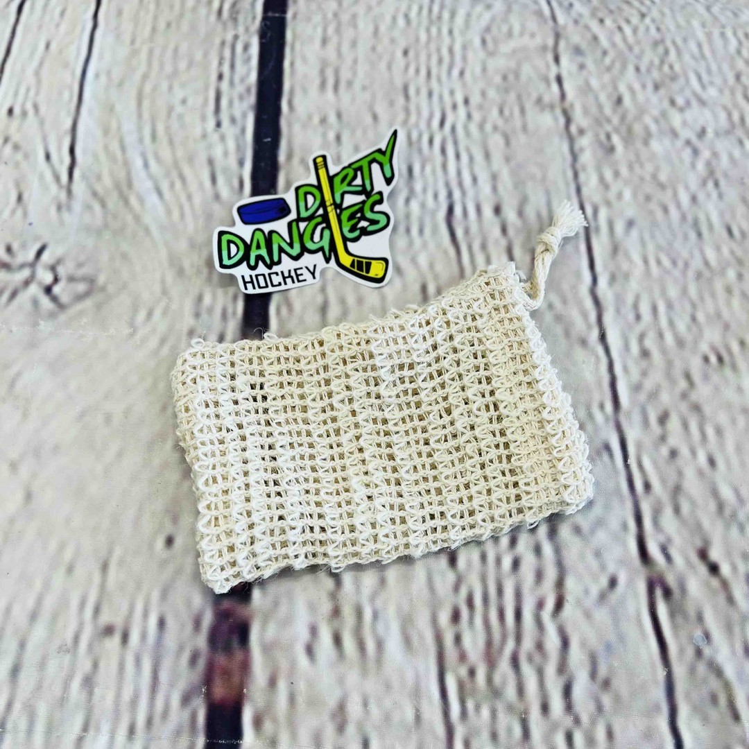 a tan sisal soap bag on a wood background with a dirty dangles hockey sticker