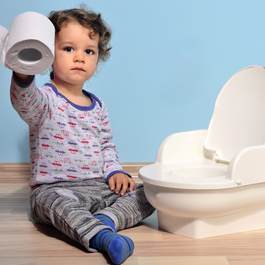 boy holding a toilet roll sitting next to a potty