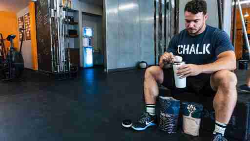 man drinking a protein shake in the gym after a workout