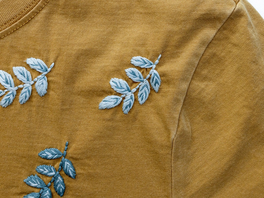 Stitched fern designs are displayed on a shirt.