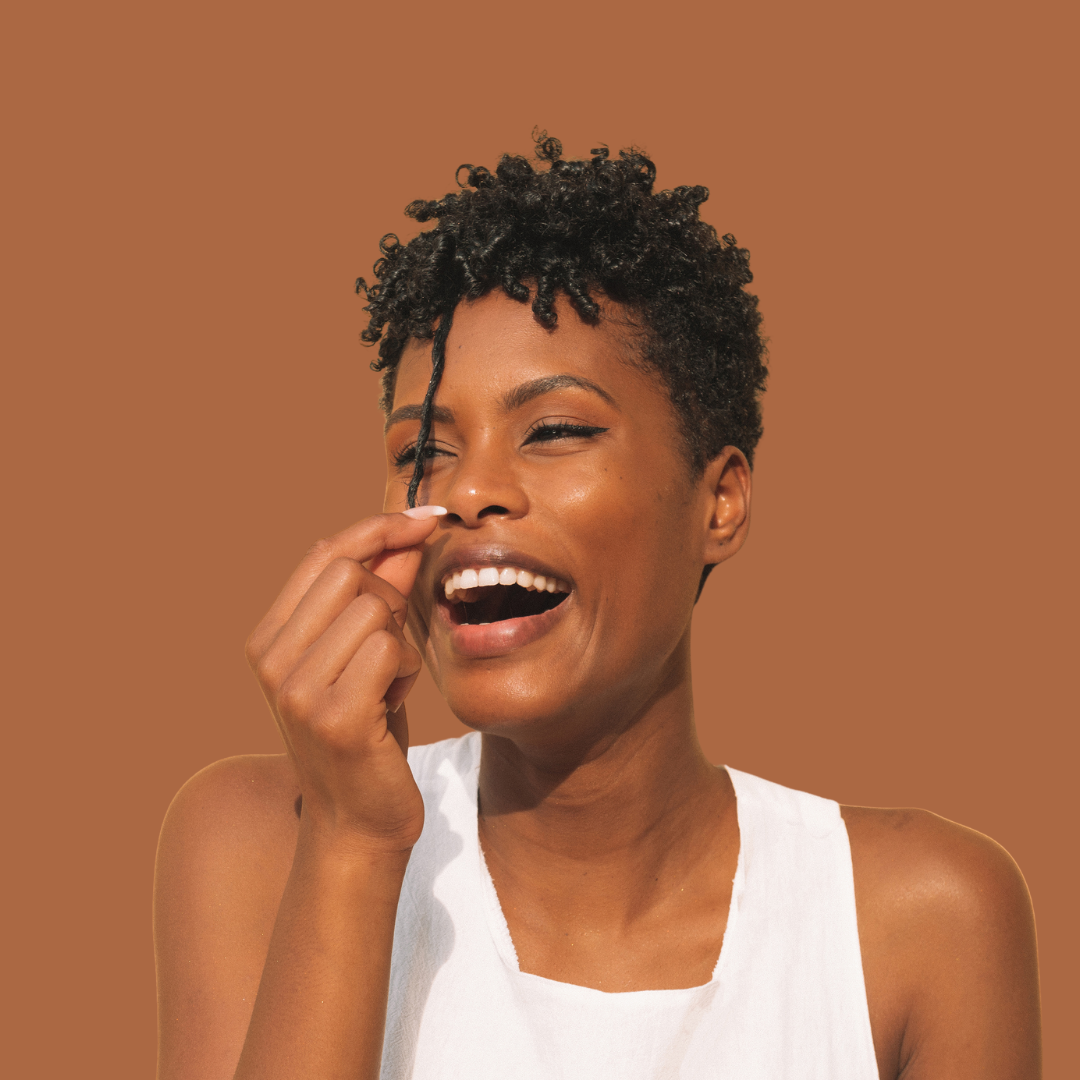 Black woman 50+ smiling with natural curls restored through Signature Hair Care Blueprint™ coaching.