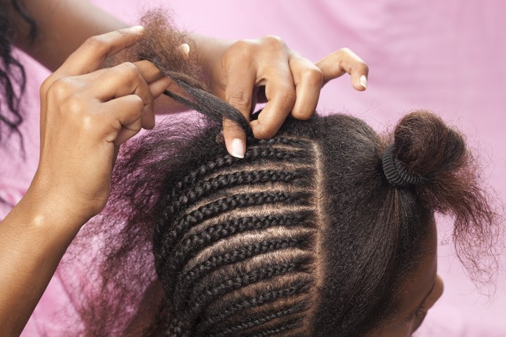 Black woman getting her hair braided