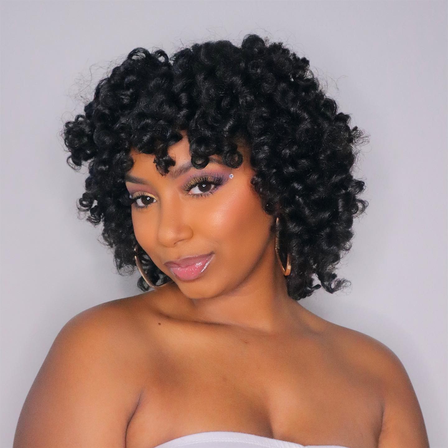 woman with a smooth and bouncy flexi rod set natural hairstyle holding a leave in moisturizing cream for natural hair