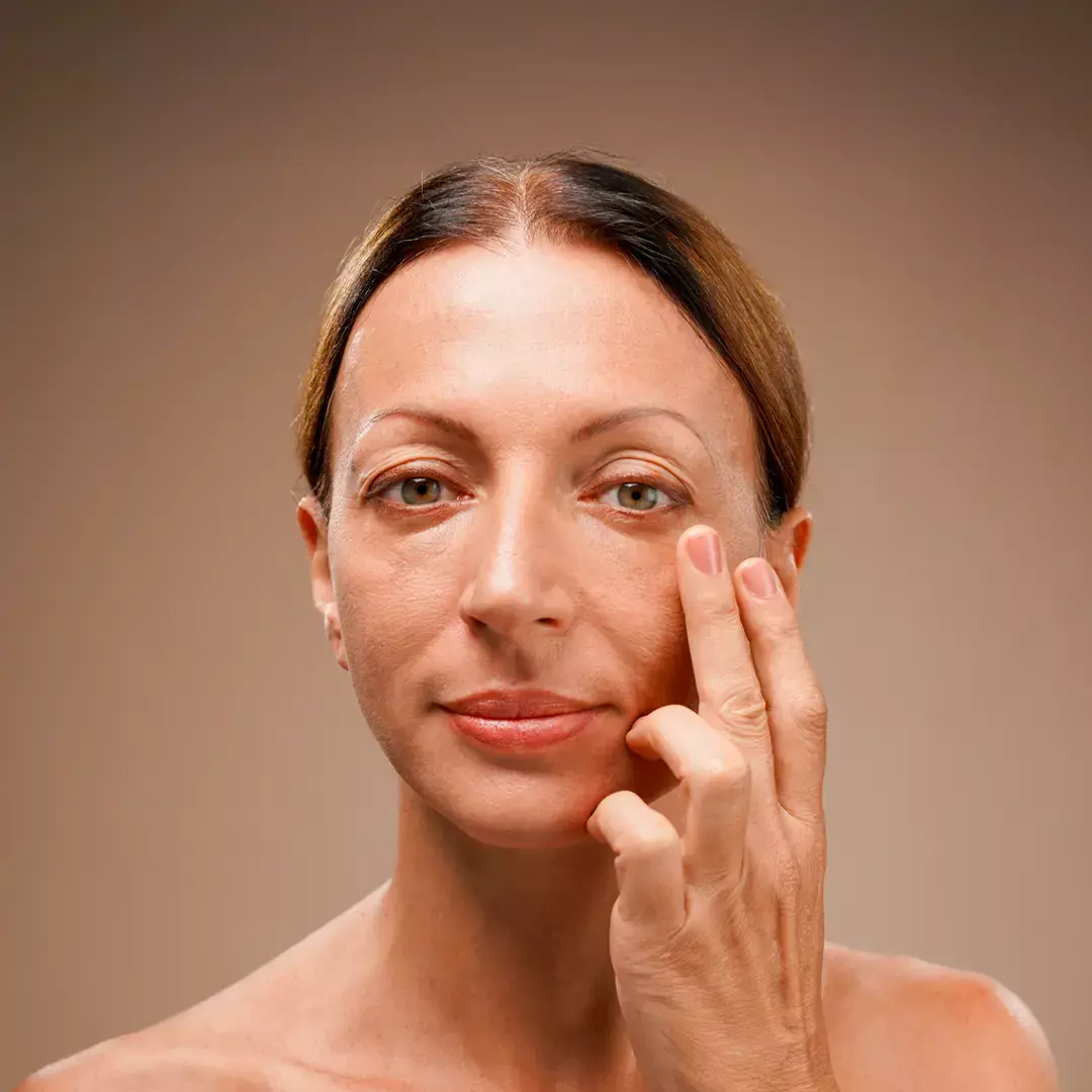 A woman dabbing the serum on her face