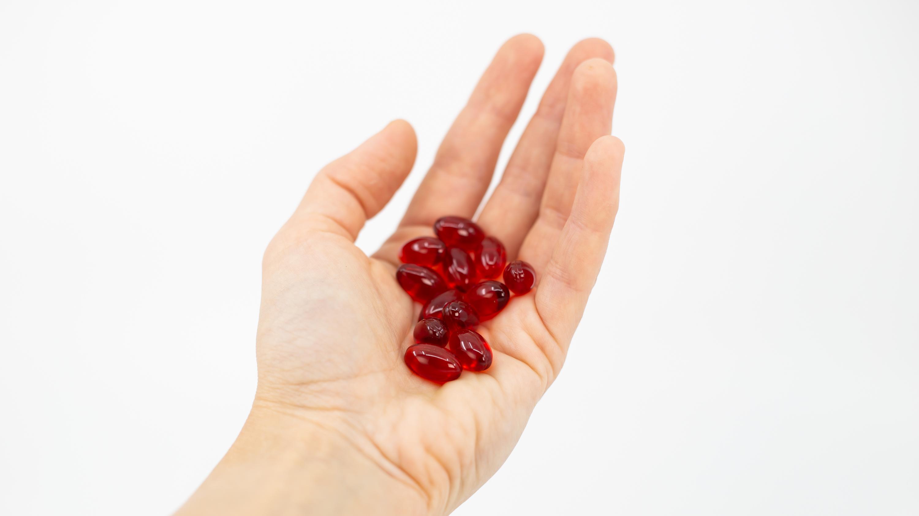 Close-up of a hand holding Glomega omega-3 soft gel capsules.