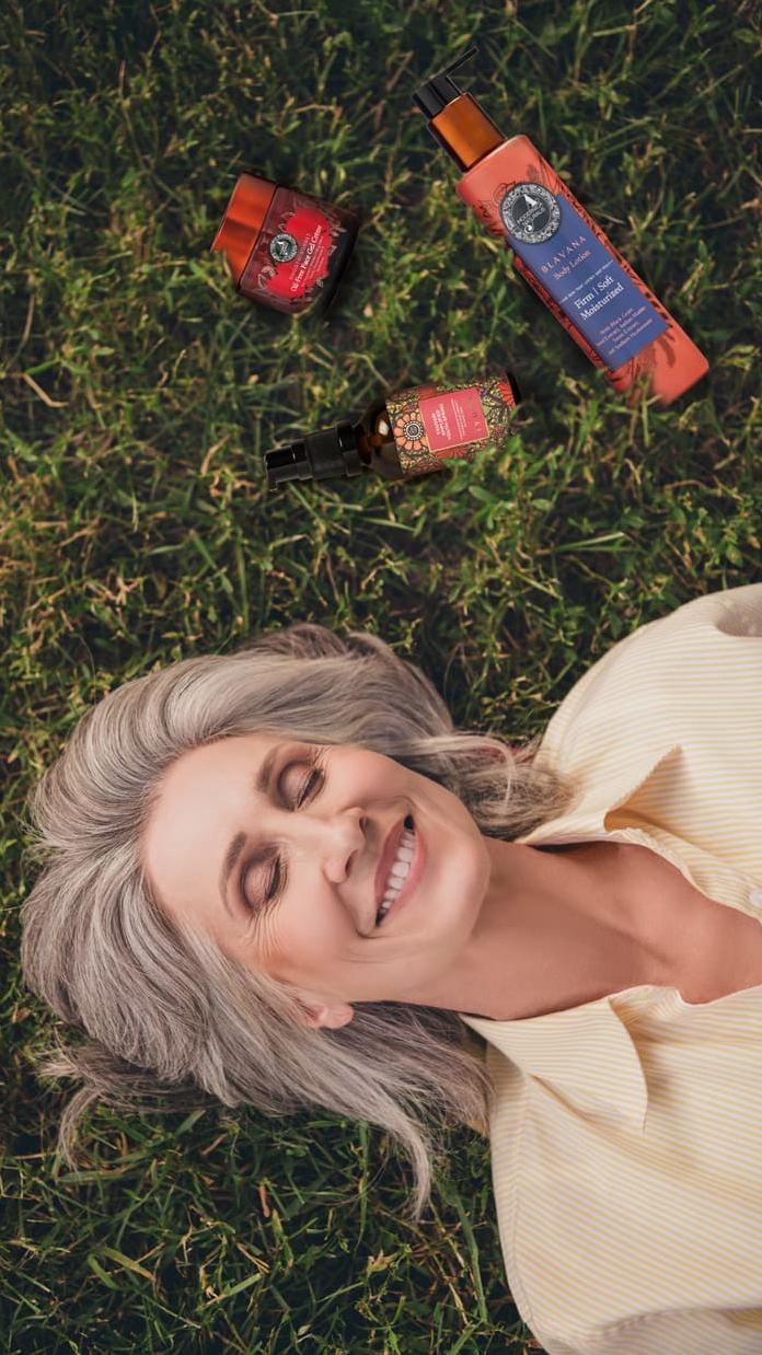 Woman lying on the grass with Blavana Body Lotion; Smooth-Sorbet and Yauvari Amplified Youth Spring