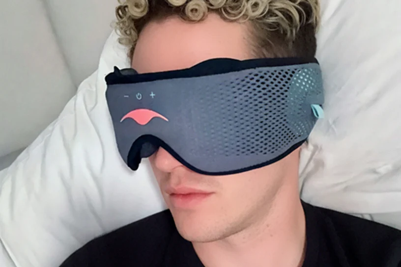 A man listening to binaural beats for sleep via a sleep mask with headphones.