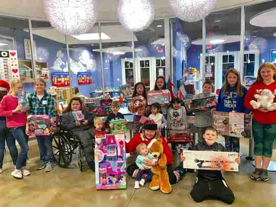 A group of kids at a hospital with presents.