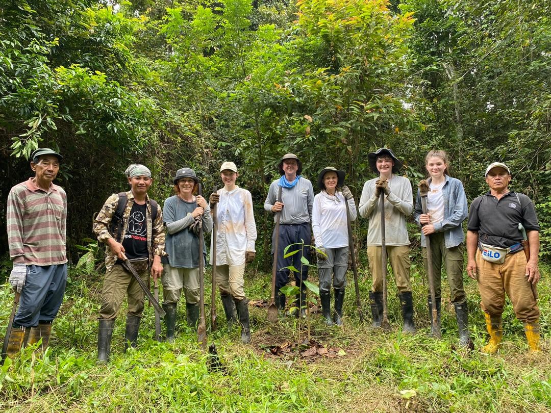 Group of 9 people standing in the forest after planting trees.