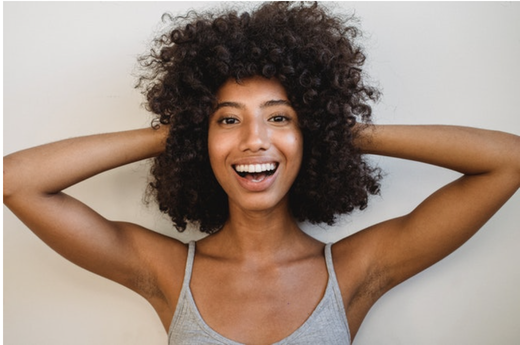 BLACK WOMAN SMILING AND HOLDING HER HAIR