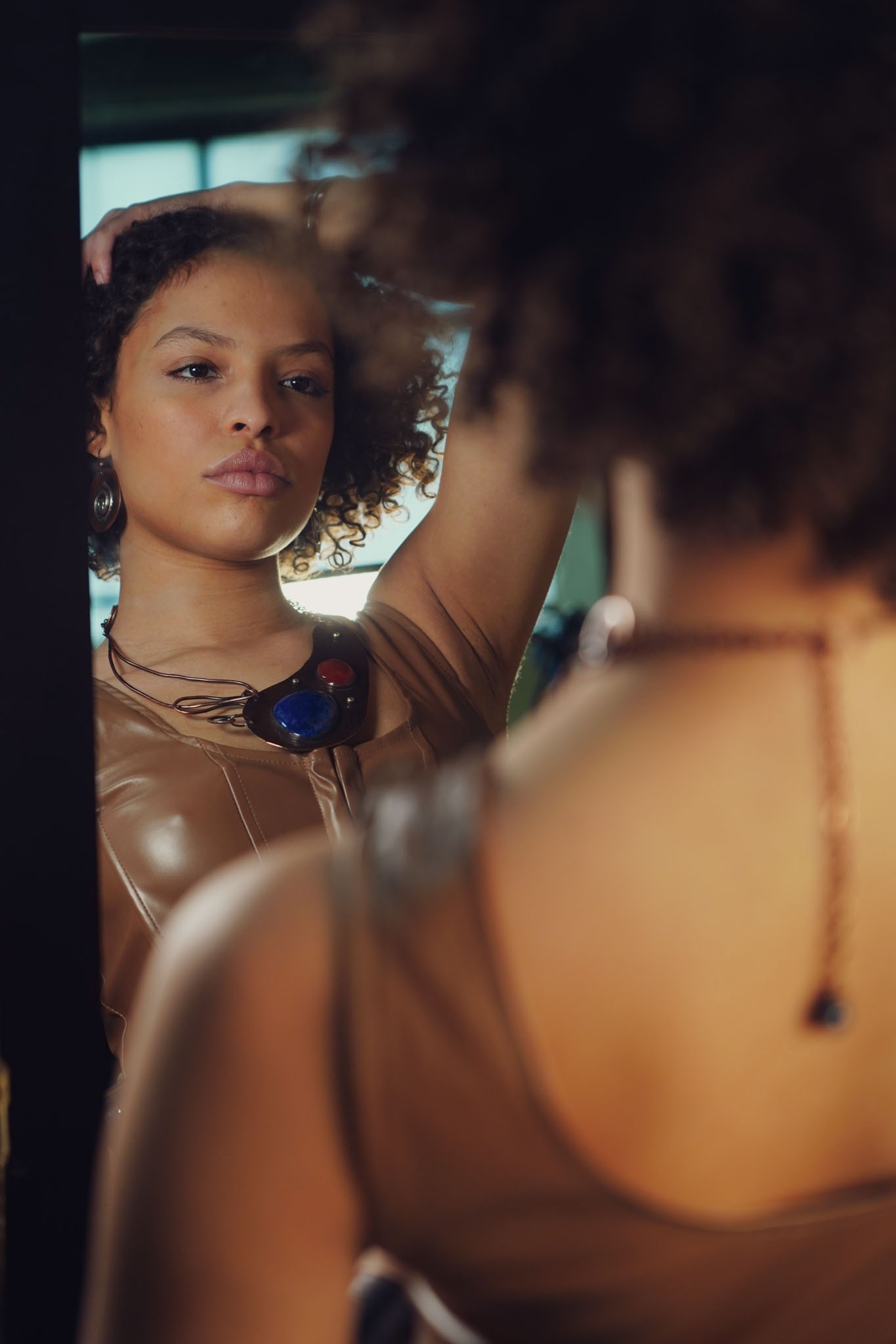 A Model looking into a mirror wearing The Statement Necklace in Lapis and Carnelian by Junebug Jewelry Designs