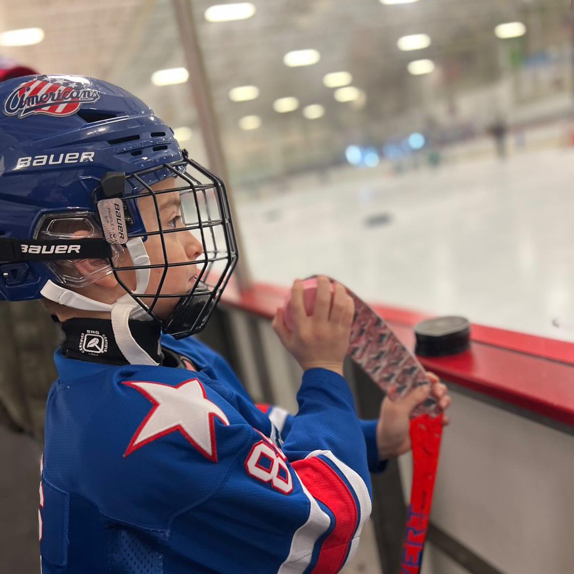 a youth hockey player applying dirty dangles hockey stick wax to a taped blade