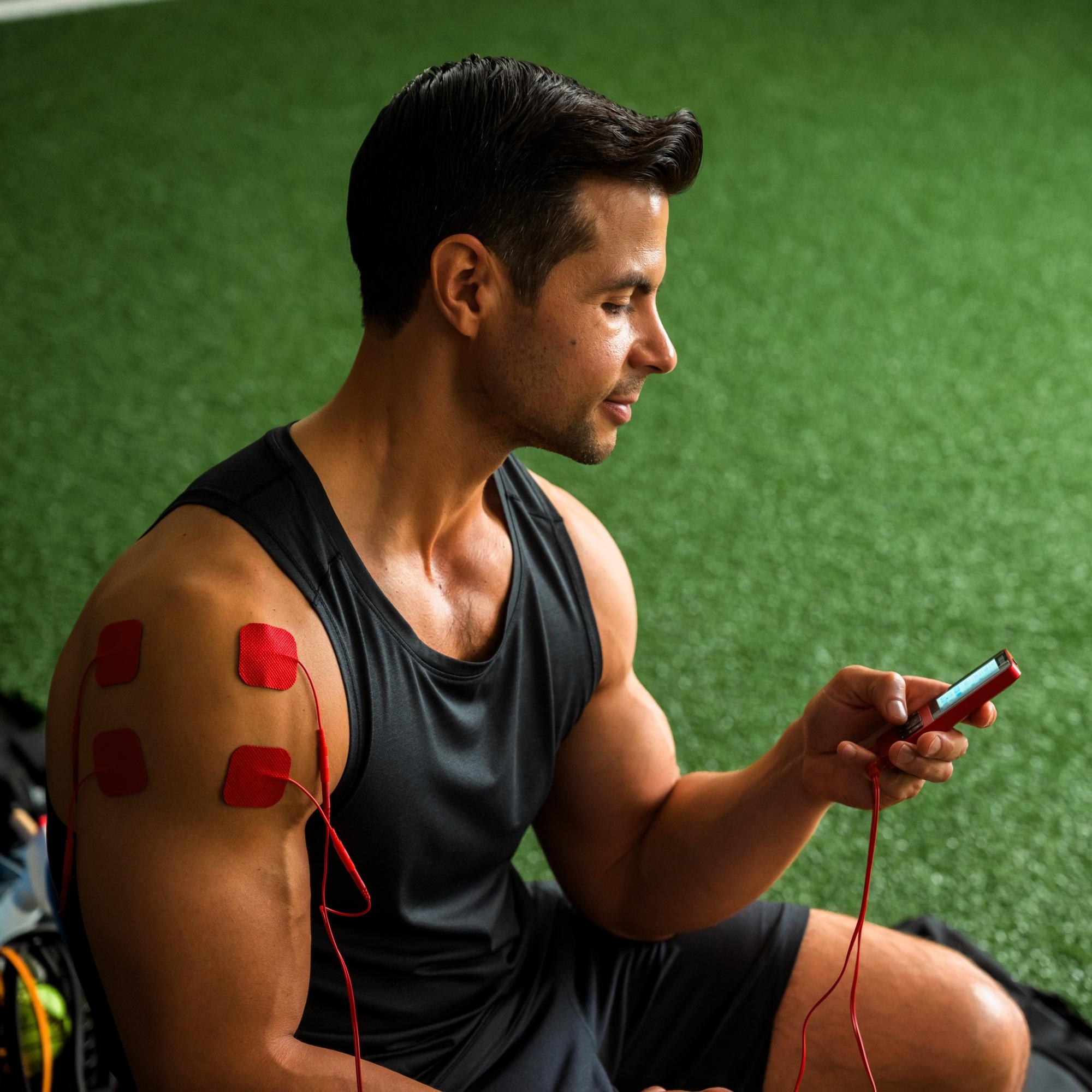 A male athlete using the TENS 7000 sports TENS unit on his shoulder