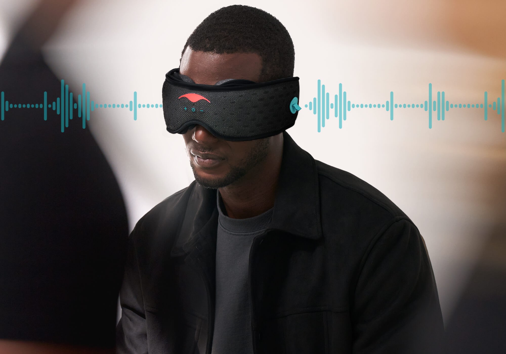 A man in a black shirt wearing a mens sleep mask with built-in Bluetooth speakers.