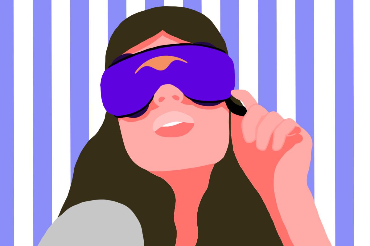 A girl holding the edge of a blue silk luxury sleep mask.