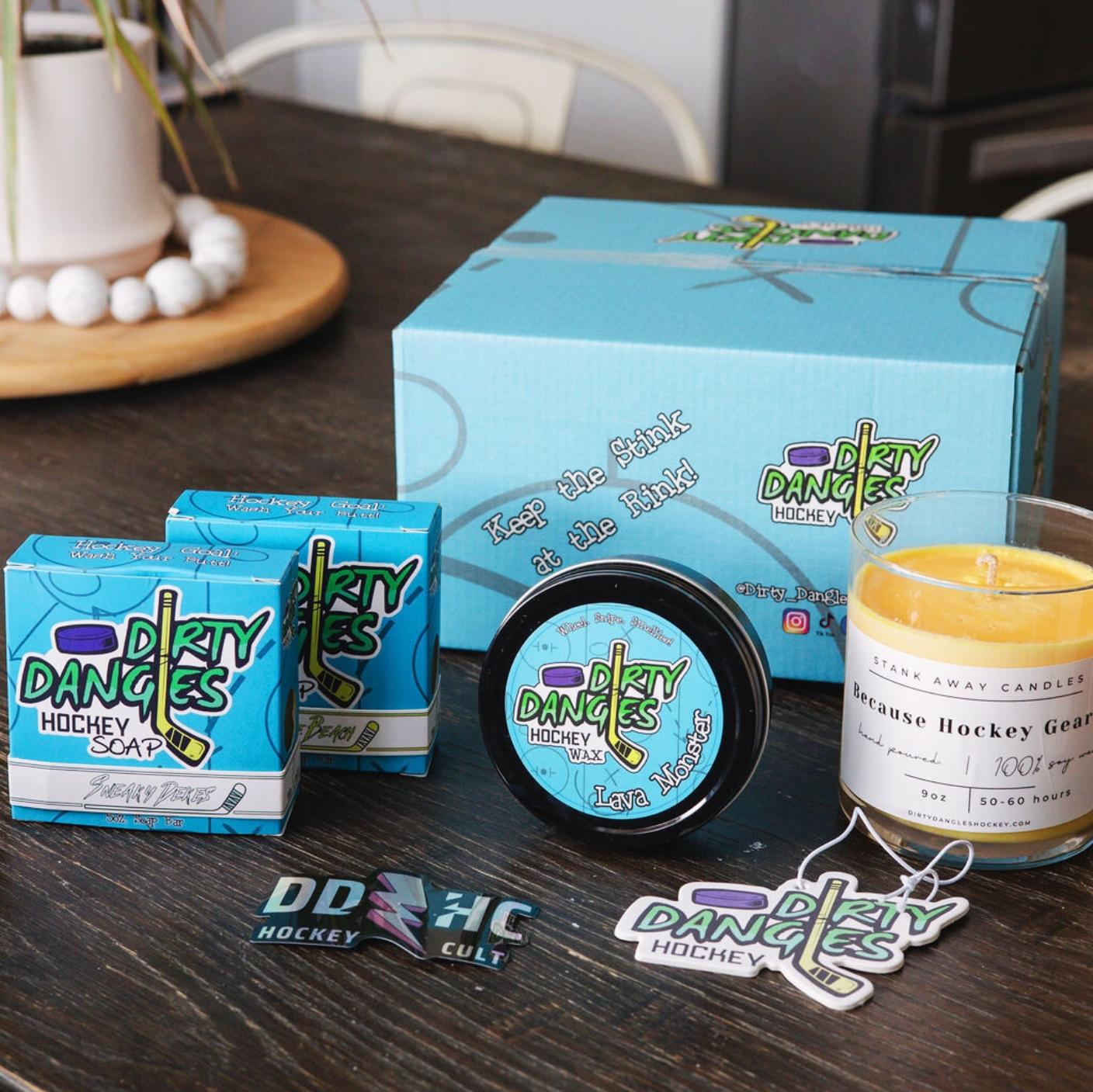 Assorted Dirty Dangles hockey products on a wood table with a blue dirty dangles subscription box.