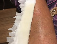 Customer's arm with a healthy glow, showcasing the hydrating effect of Bella Terra Oils on skin, against a backdrop of white ruffled fabric.