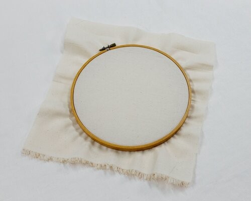 This image shows step 2 of dressing your hoop, putting the fabric in the hoop.