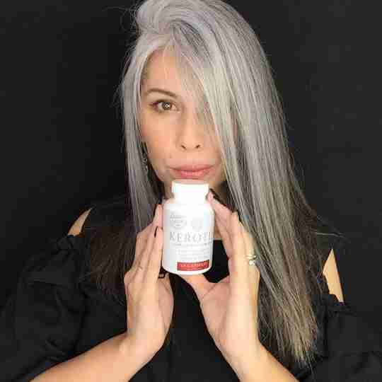 Model With Long Gray Hair Holding a Bottle of Kerotin Hair Vitamins