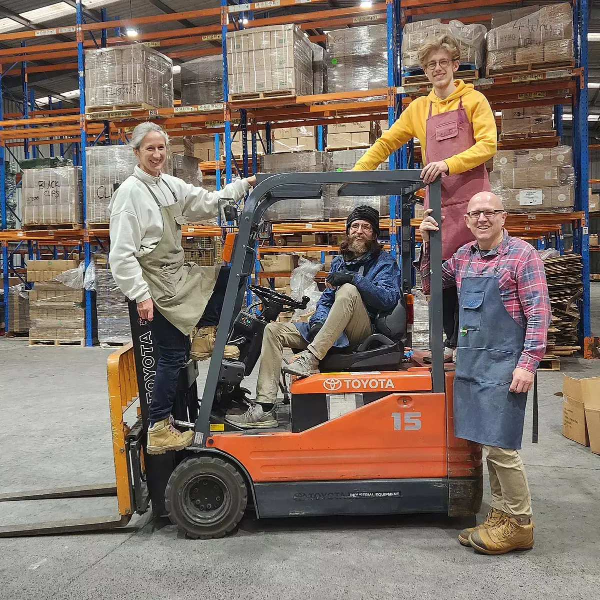 Aussie Gardener team standing with a forklift inside a warehouse during EOFY clearance.