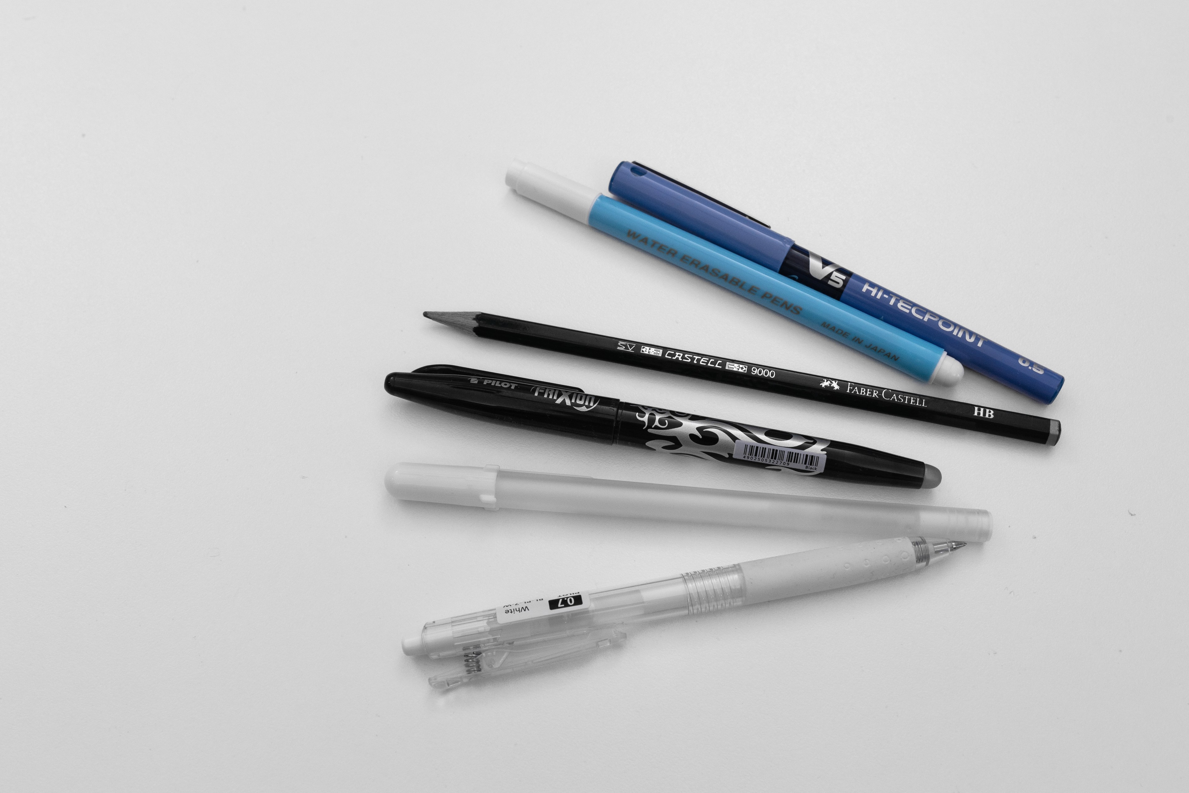 Transfer pens and pencils lay next to each other on a white background.