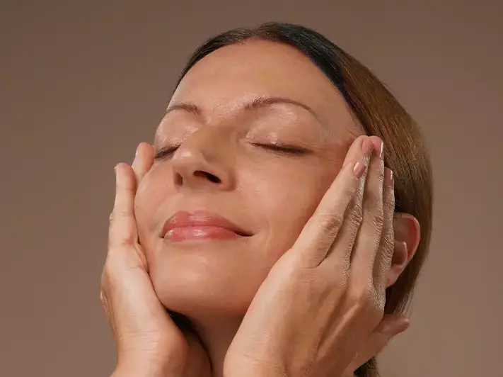 A woman massaging her face with serum