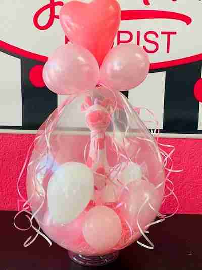 A pink giraffe inside a large pink balloon filled with pink and white balloons