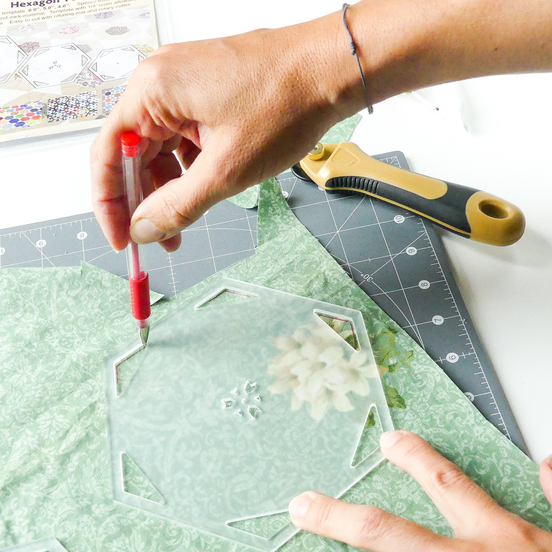 Marking lines in the triangular seam allowance slots of a hexagon quilt template.