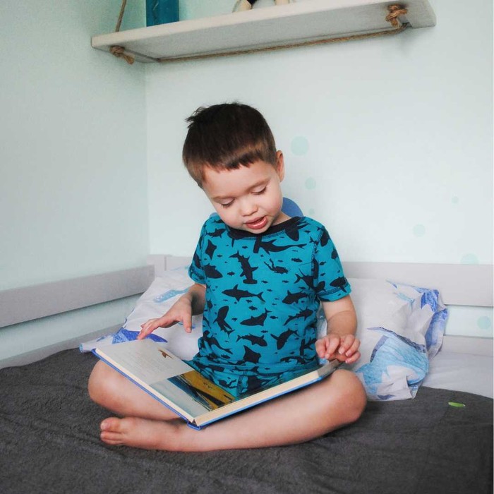Boy reading a book on waterproof bed mat PeapodMat