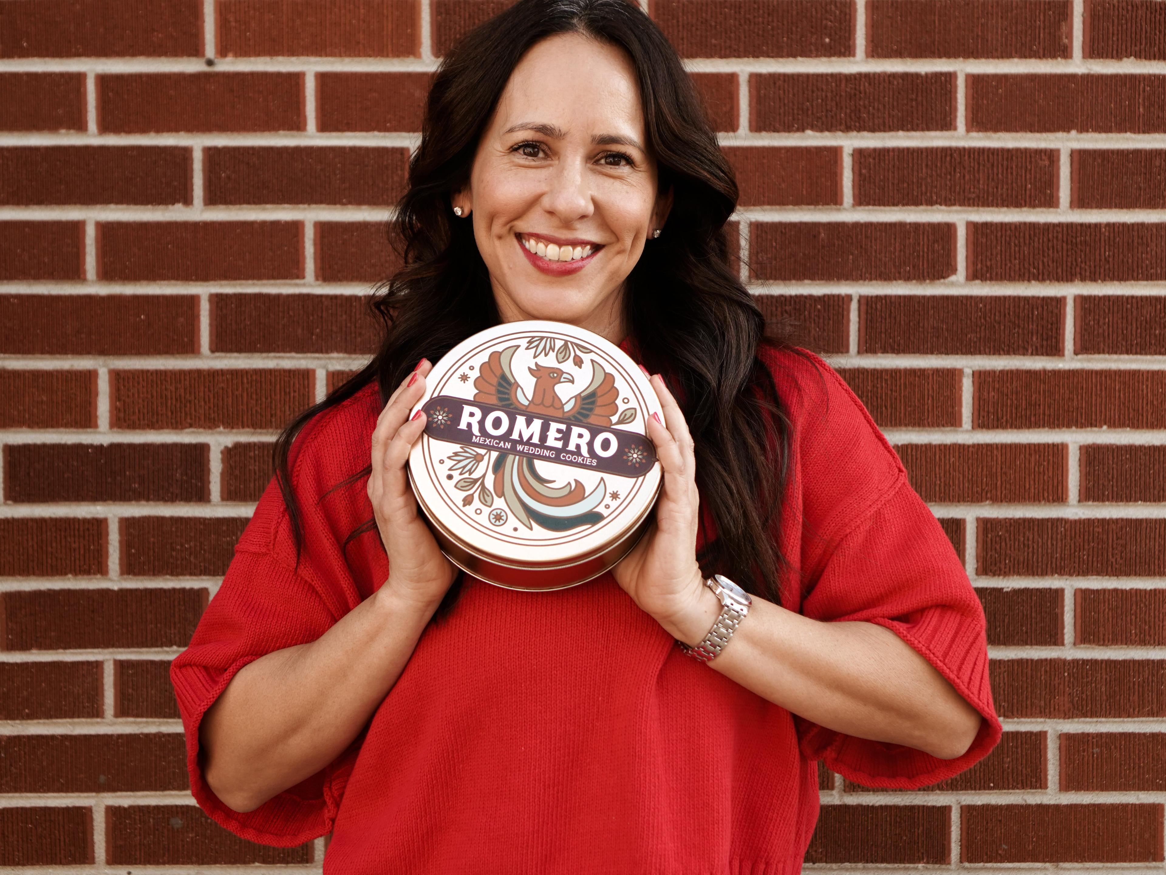 women holding up cookie tin in front of brick wall