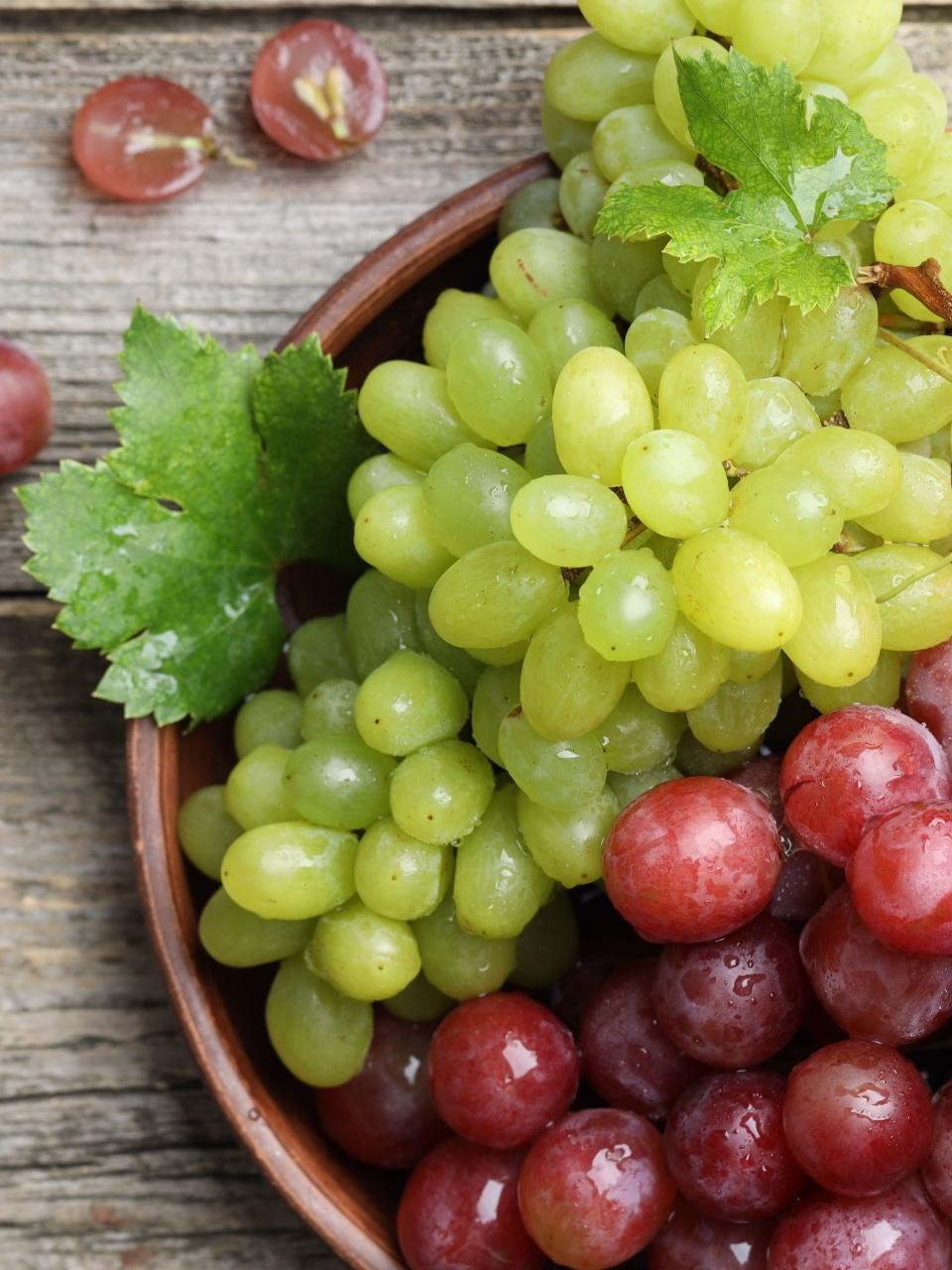 Fresh ripe grapes and glasses of wine on wooden table, flat lay