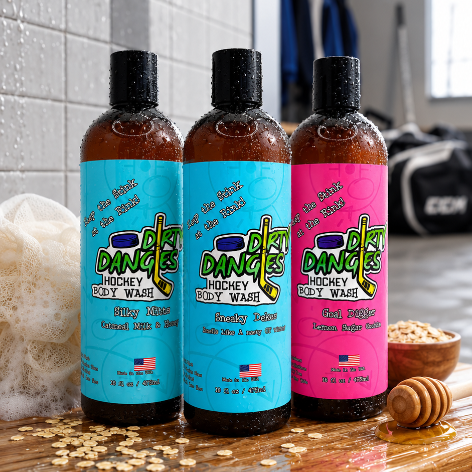 3 bottles of dirty dangles hockey body wash on a bench in a locker room with a loofah, honey and oats