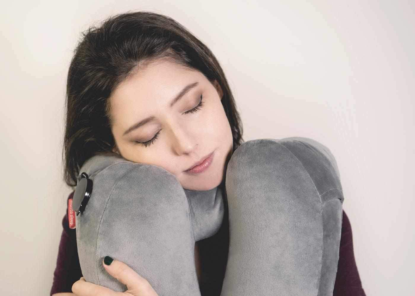 A girl napping on a gray travel pillow.