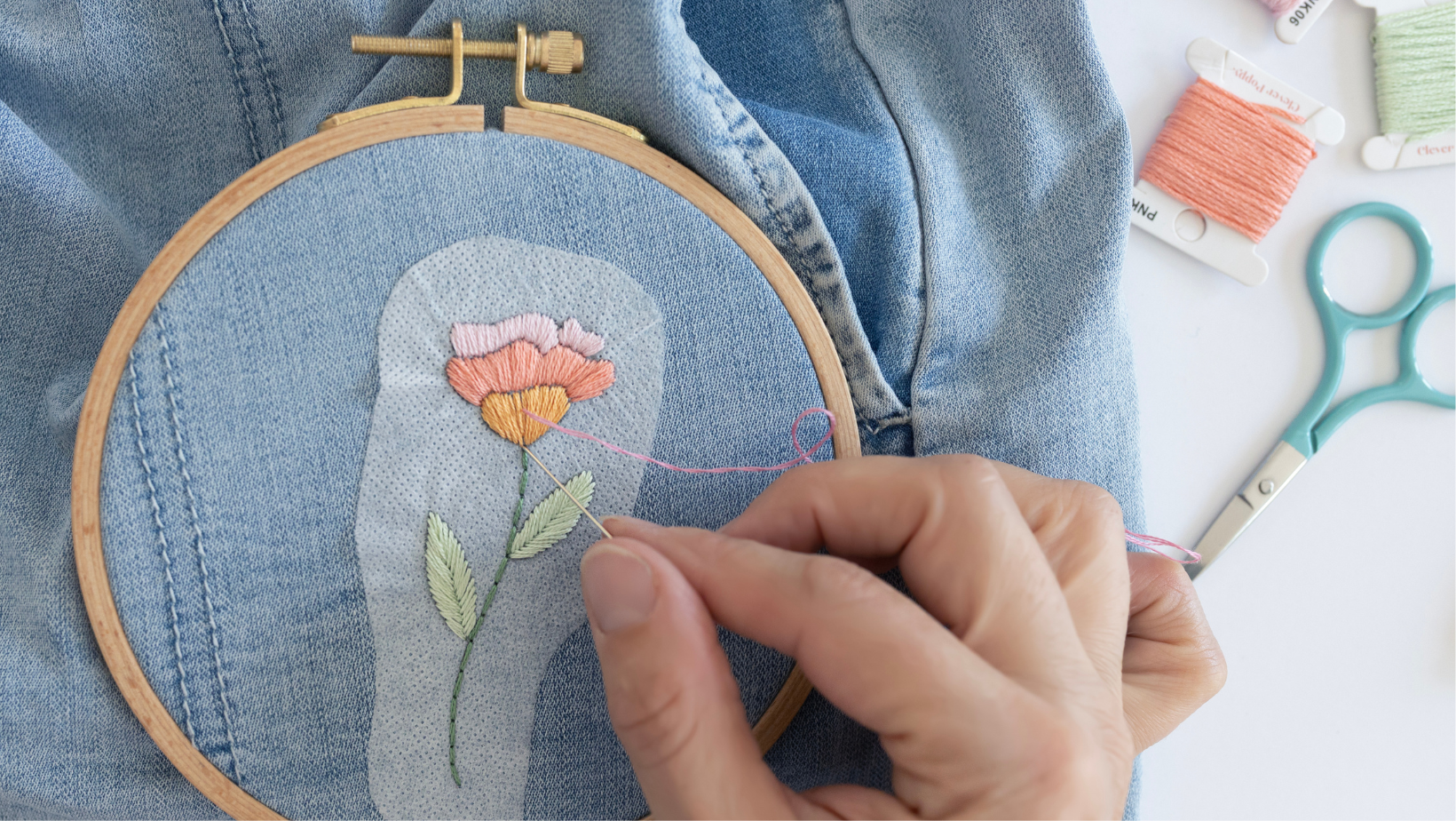 A wash away embroidery sticker being stitched onto denim shorts.