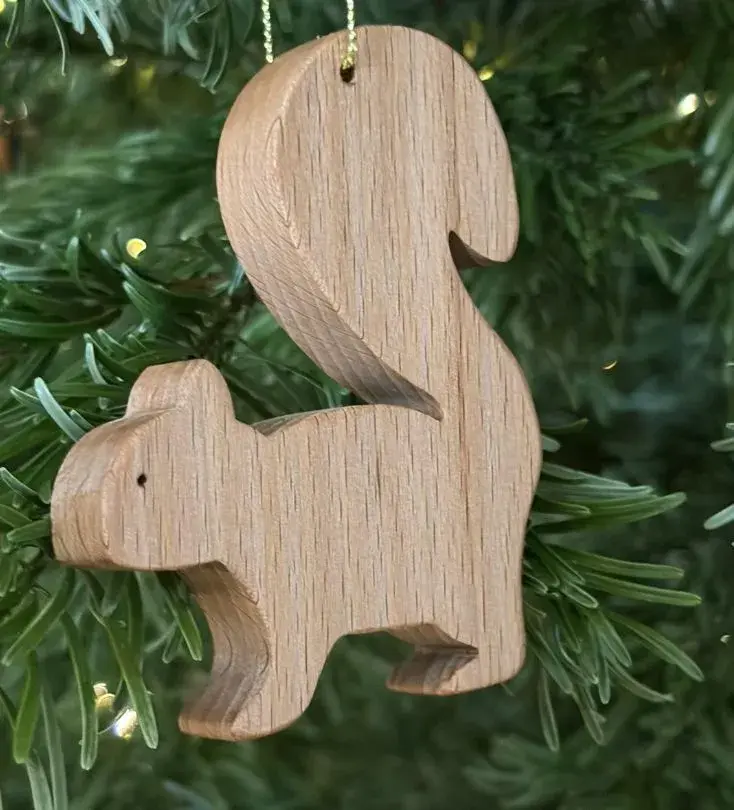 A wooden squirrel ornament hangs from a Christmas tree, adding a whimsical touch to the festive decorations.