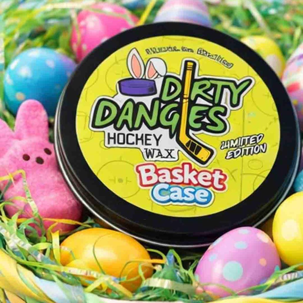 A tin of dirty dangles hockey wax basket case scent in an easter basket with green easter grass