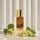 Beaut'Air perfume bottle with white linden blossoms against a cream pleated curtain