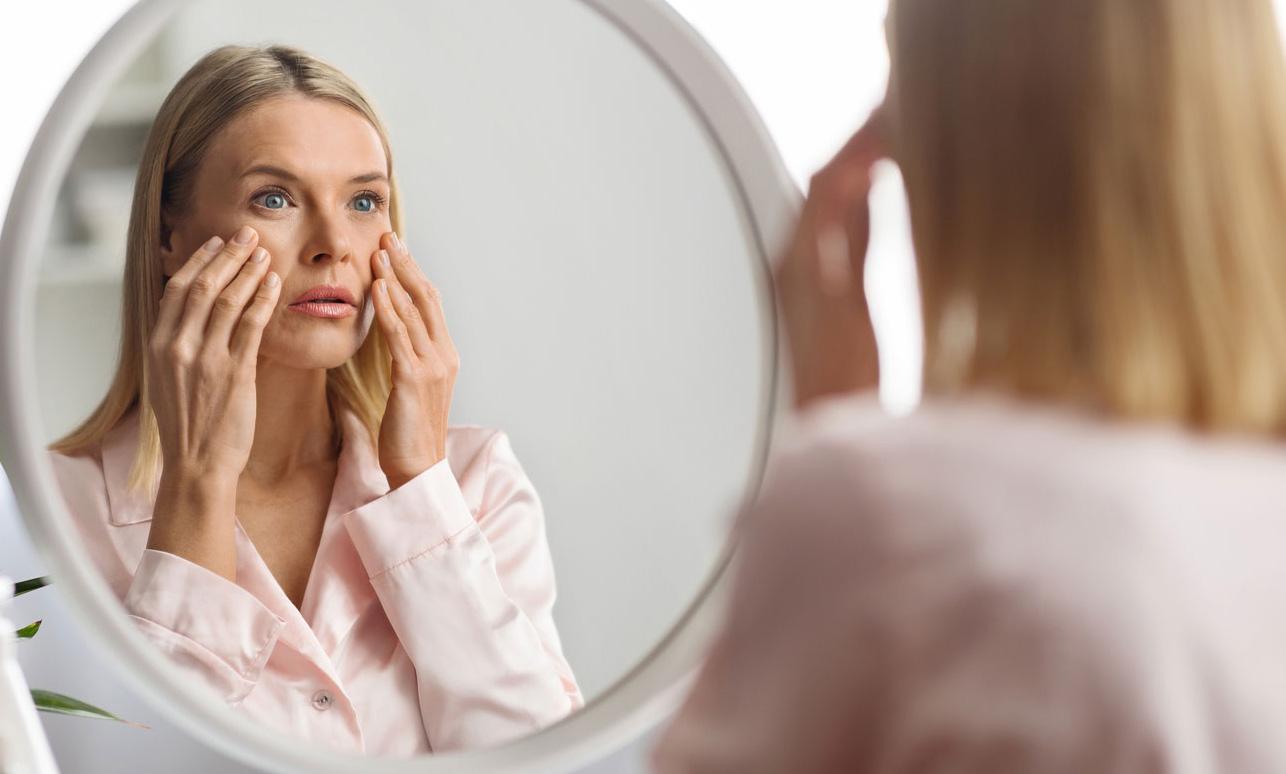 Mature woman carefully looking at her reflection on the mirro