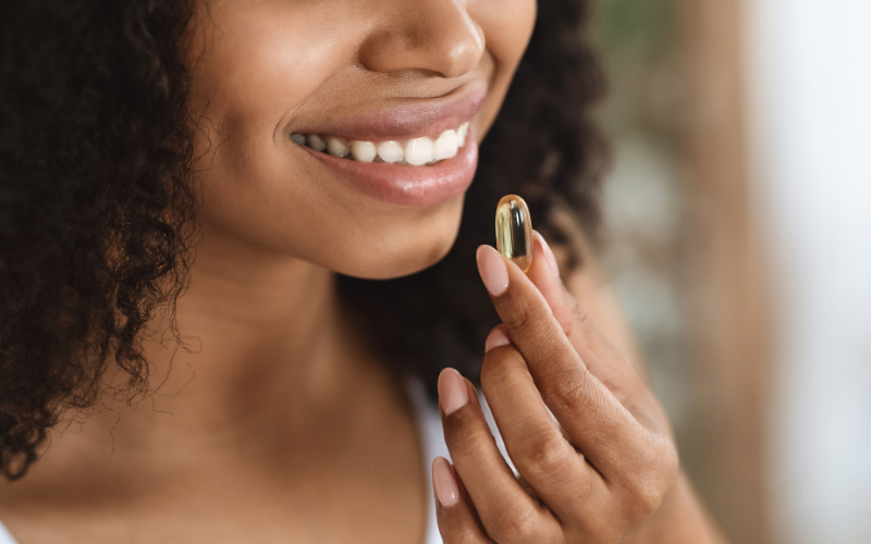 black woman holding a supplement to her moutn
