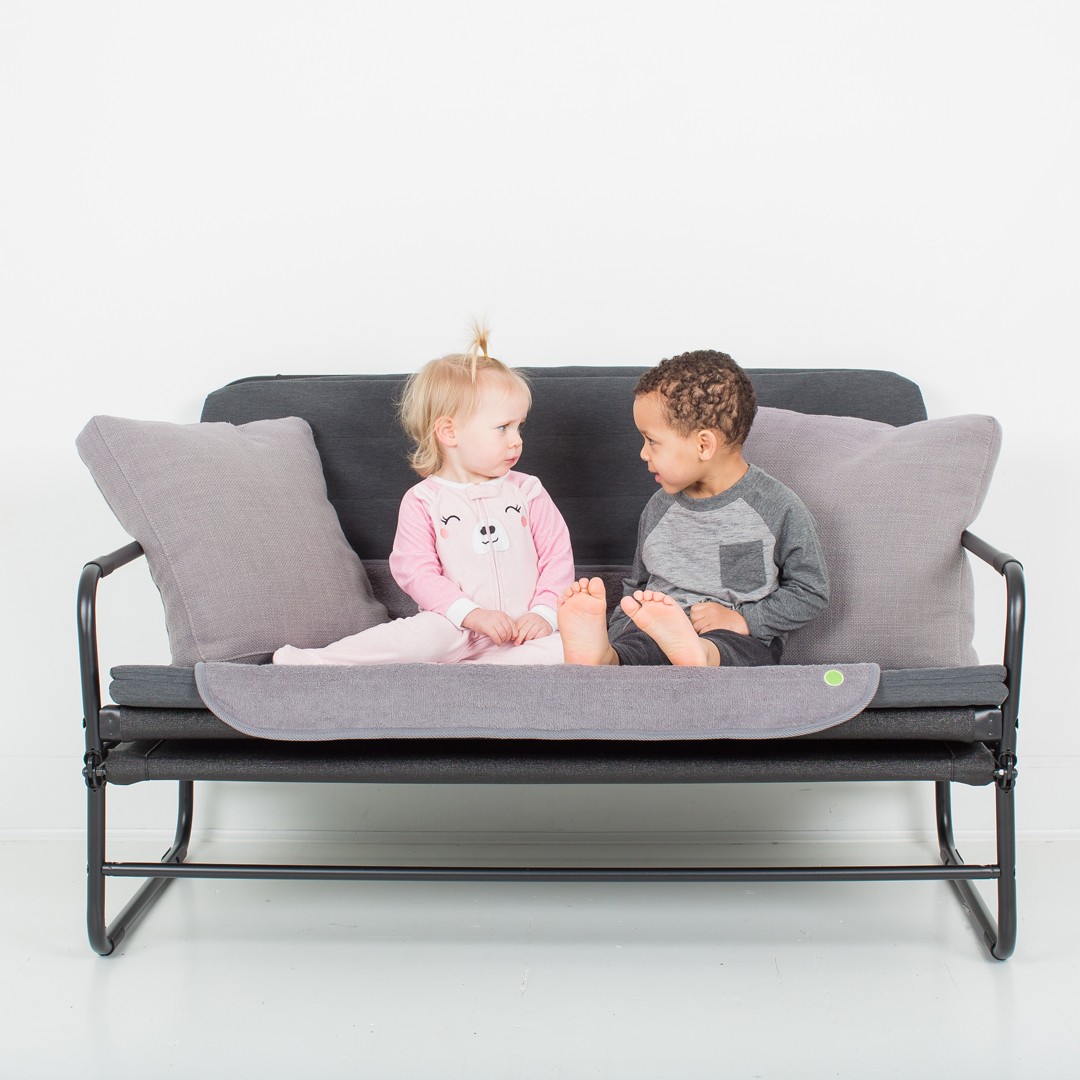 Toddlers sitting on a sofa with PeapodMat