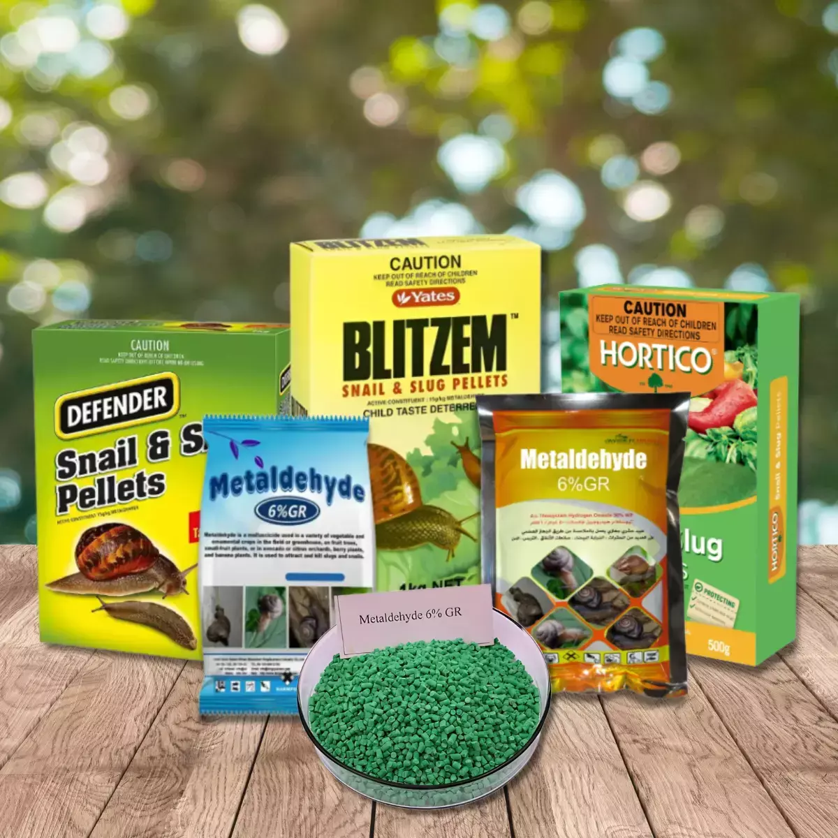 Assorted snail and slug bait products containing metaldehyde displayed on a wooden surface, with a bowl of green pellets in front.
