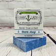 Picture of a box of Shart Wash Natural Handmade Bar Soap Sharts Ahoy! scent sitting on a blue bar of soap with a wood background